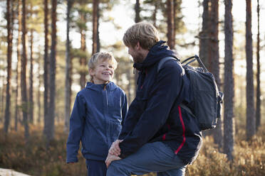 Father and son talking in forest, Finland - CUF53548