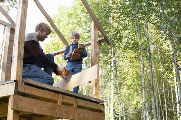 Vater und Sohn bauen gemeinsam ein Baumhaus im Garten - CUF53563