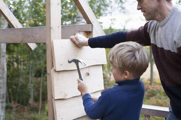 Father and son building treehouse together in garden - CUF53565