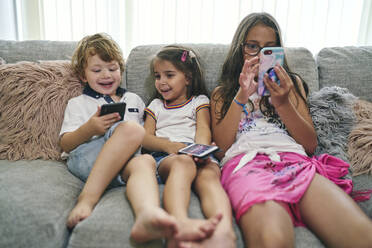 Freunde genießen Computerspiele auf dem Sofa - CUF53653