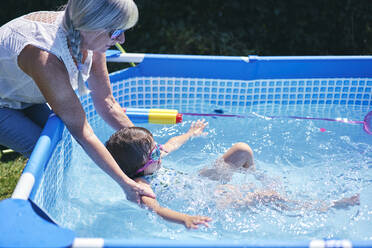 Großmutter stützt Enkelin im Pool - CUF53659