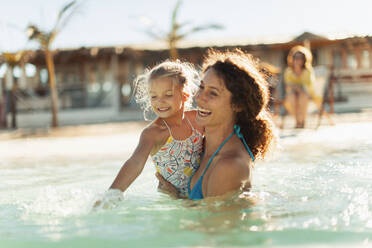 Happy mother and daughter swimming in sunny ocean - HOXF04528