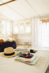 Suitcase, sun hat, sunglasses and book on beach hut bed - HOXF04604