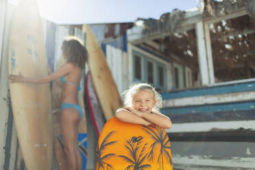 Portrait süßes Mädchen mit Bodyboard am sonnigen Strand - HOXF04616