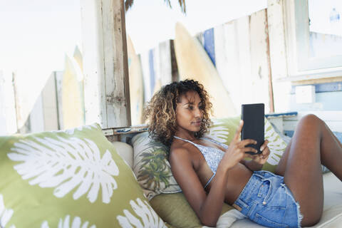 Junge Frau benutzt digitales Tablet auf einer Strandterrasse, lizenzfreies Stockfoto