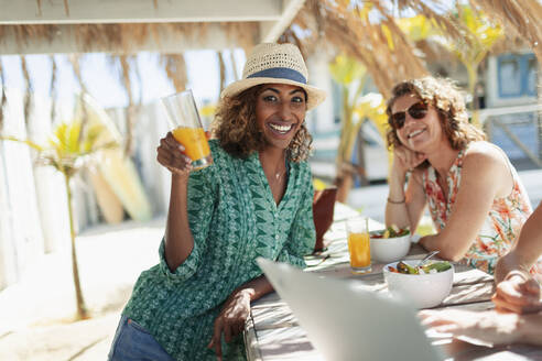 Porträt einer glücklichen Frau, die einen Cocktail an einer sonnigen Strandbar trinkt - HOXF04640