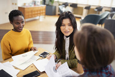 Businesswomen discussing paperwork in meeting - HOXF04649
