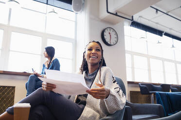 Happy, confident businesswoman with paperwork in office - HOXF04658