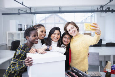 Businesswomen moving into new office, taking selfie - HOXF04687