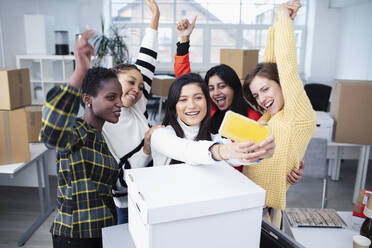 Happy businesswomen moving into new office, taking selfie - HOXF04701