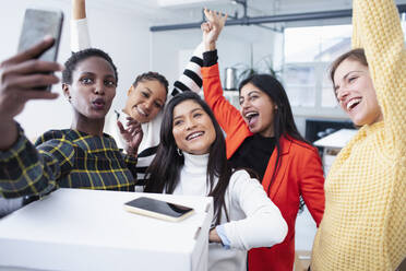 Happy businesswomen celebrating new office, taking selfie - HOXF04708