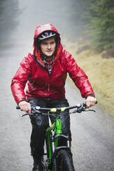 Mann beim Mountainbiken im Regen - HOXF04726