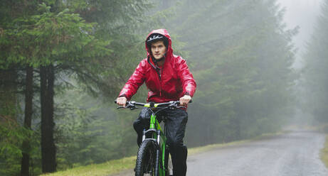 Mann beim Mountainbiken im Regen - HOXF04731
