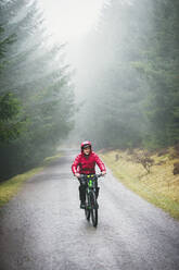 Mann beim Mountainbiken im Regen - HOXF04737