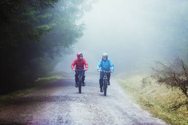 Father and son mountain biking in woods - HOXF04756