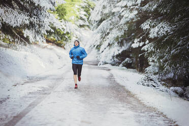 Mann joggt im verschneiten Wald - HOXF04771