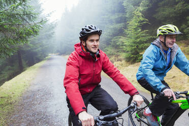 Vater und Sohn beim Mountainbiking im Wald - HOXF04773