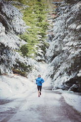 Mann joggt im verschneiten Wald - HOXF04784