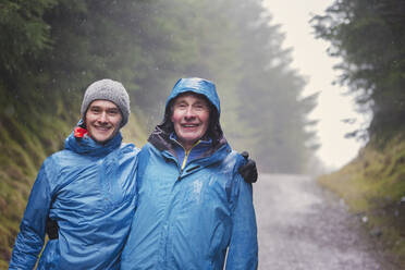 Portrait father and son hiking in rain - HOXF04787