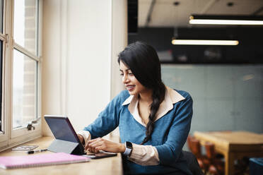 Geschäftsfrau arbeitet am digitalen Tablet im Büro - HOXF04810