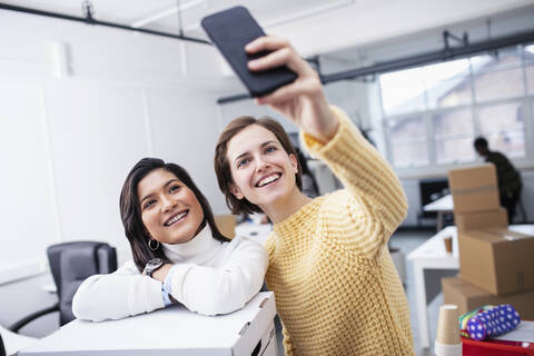 Smiling businesswomen taking selfie in new office stock photo