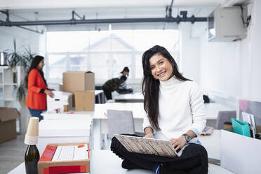 Porträt einer lächelnden, selbstbewussten Geschäftsfrau, die in einem neuen Büro einen Laptop benutzt - HOXF04833