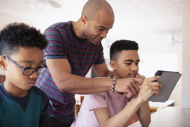 Vater und Sohn im Teenageralter benutzen ein digitales Tablet - HOXF04870