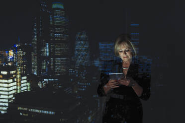 Doppelbelichtung Geschäftsfrau mit digitalen Tablet gegen Hochhaus Lichter in der Nacht - CAIF23400