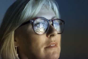 Close up reflection of computer screen in focused businesswoman's eyeglasses - CAIF23403