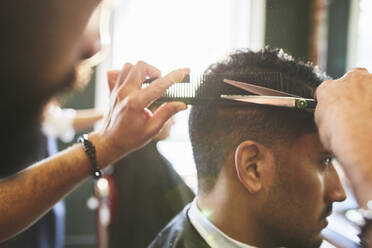 Männlicher Friseur schneidet einem Kunden die Haare im Friseursalon - CAIF23421