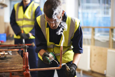 Männlicher Schüler bei der Arbeit mit Kupfer in der Werkstatt des Werkunterrichts - CAIF23450