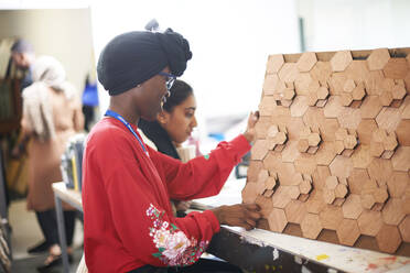 Female artist with 3D wood art in art studio - CAIF23478