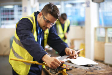 Ein männlicher Schüler benutzt einen Zollstock in der Werkstatt des Werkunterrichts - CAIF23488