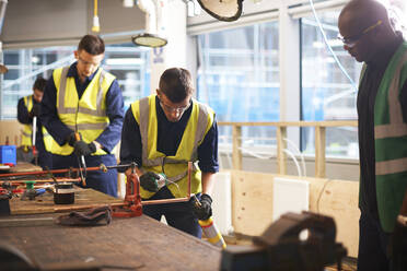 Male instructor watching student welding in workshop - CAIF23491