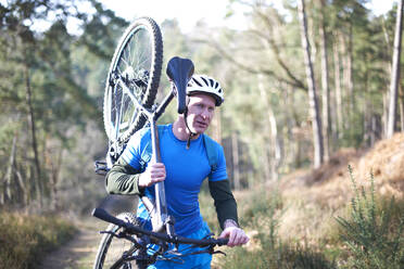 Männlicher Radfahrer mit Fahrrad auf einem sonnigen Weg im Wald - CAIF23521