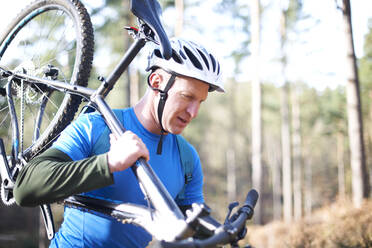 Männlicher Radfahrer mit Fahrrad im sonnigen Wald - CAIF23524