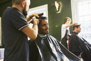 Lächelnder Mann erhält Haarschnitt beim Friseur - CAIF23534