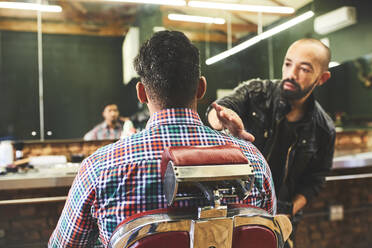 Männlicher Friseur überprüft den Haarschnitt eines Kunden in einem Friseursalon - CAIF23537