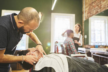 Männlicher Friseur rasiert das Gesicht eines Kunden im Friseursalon - CAIF23565