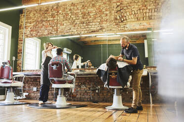 Male barbers and customers in barbershop - CAIF23577
