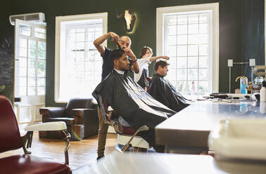 Männlicher Friseur, der einem Kunden im Friseursalon die Haare schneidet - CAIF23585
