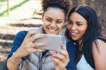 Happy young women friends taking selfie with smart phone - CAIF23590