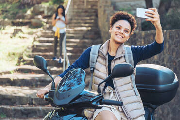 Junge Frau nimmt Selfie mit Kamera-Handy auf Motorroller - CAIF23602