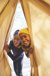 Verspielte Geschwister spähen in ein Camping-Tipi - CAIF23618