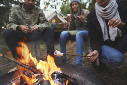 Familie röstet Marshmallows am Lagerfeuer auf dem Campingplatz - CAIF23619
