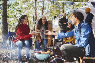 Glückliche Familie beim Essen auf dem sonnigen Campingplatz - CAIF23621