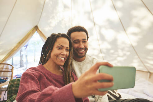Glückliches Paar macht Selfie in Camping-Jurte - CAIF23624