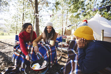 Lesbisches Paar und Kinder kochen Frühstück am Grill auf dem Campingplatz im Wald - CAIF23632