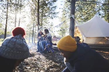 Lesbisches Paar und Kinder entspannen sich auf einem sonnigen Campingplatz im Wald - CAIF23646