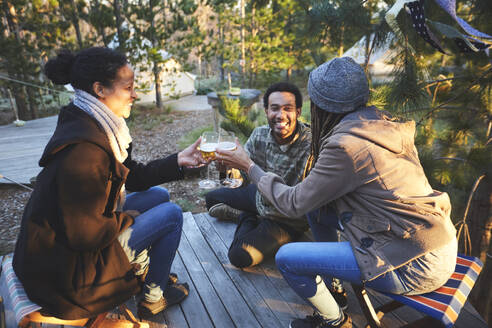 Glückliche Freunde trinken Wein auf einem Campingplatz im Wald - CAIF23659